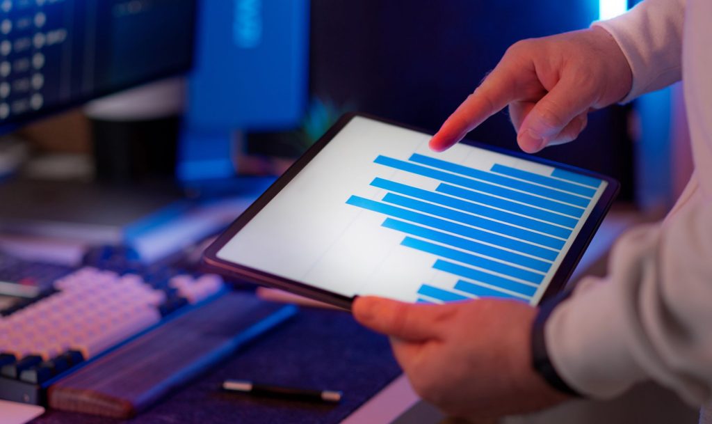 Mastering Email Deliverability: Download the Free AI Marketing Expert Plugin Today 1 Business professional analyzing bar chart on tablet in office setting, highlighting data insights.