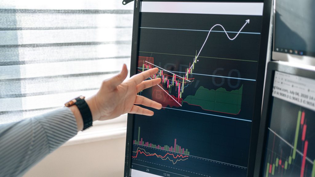 Consolidate Your Marketing Tools: How the AI Marketing Expert Plugin Revolutionizes WordPress 1 Close-up of a hand pointing at stock market graphs on a monitor in a workspace.